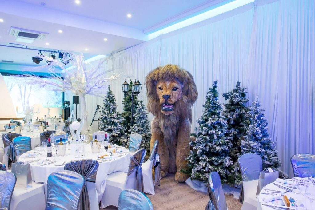 Large lion prop with Christmas trees and white draping on walls free standing lion snowy trees white artificial trees