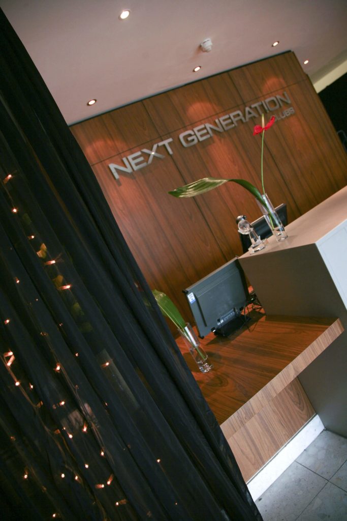 Next Generation wooden desk and black draping with fairy lights behind