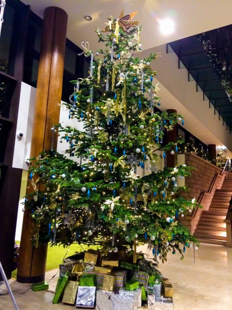 Statement Christmas tree with gold and turquoise decorations and presents beneath