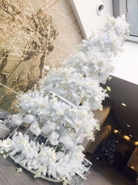 Tall statement white Christmas tree with white feathers and baubles