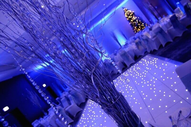 Winter table centrepiece with silver branches and jewels intwined. christmas decor with LED white dance floor