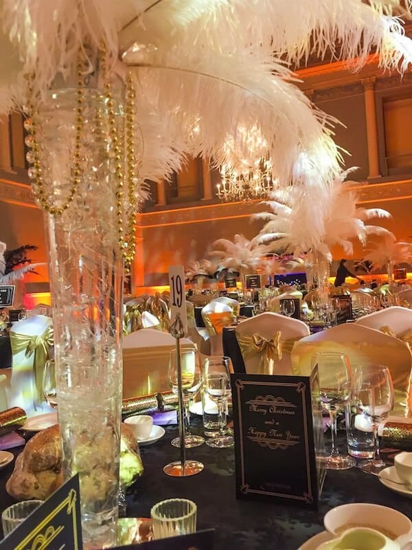 glitz and glam themed event table centres feathers white golden chair sashes orange gold lighting
