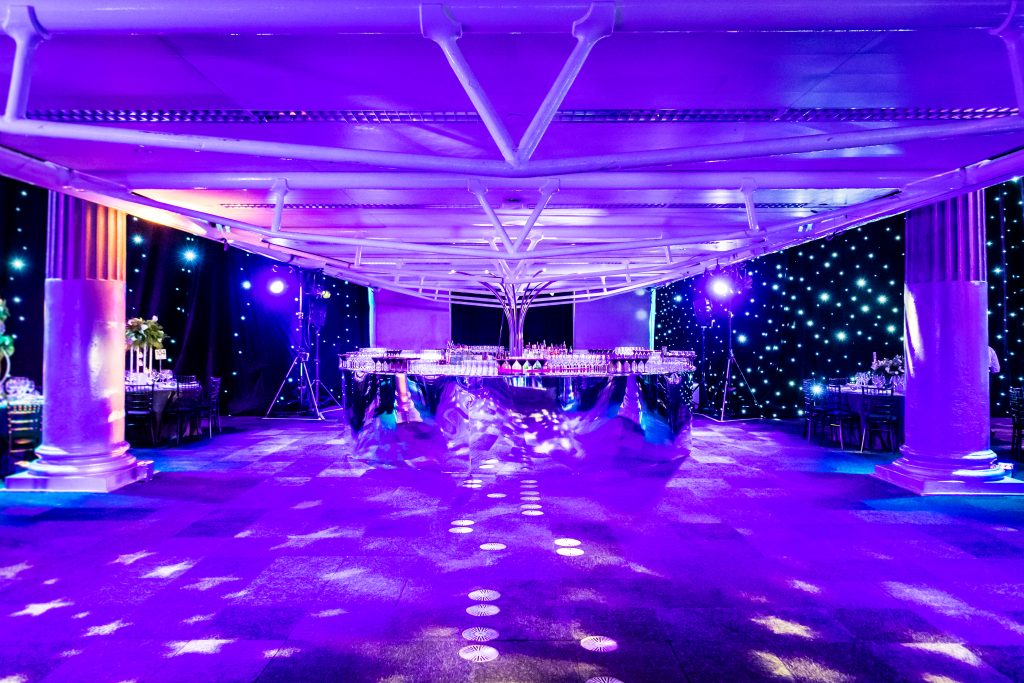 contemporary modern mirror bar with starcloth draping . purple uplighters AV